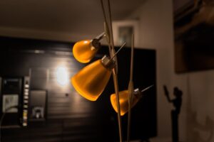 Lampadaire arc avec trois abat-jours jaunes illuminant un salon sans plafonnier
