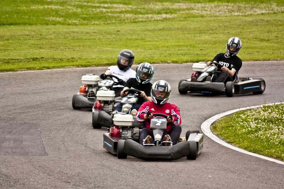 Quatre conducteurs en karting casques naviguent sur virage de circuit