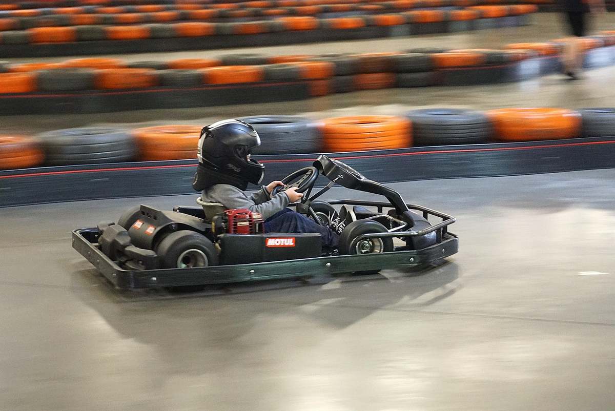 un enfant pilote un kart sur une piste intérieure