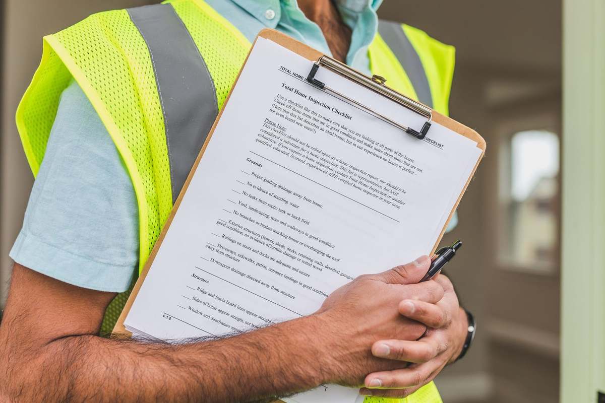 Inspecteur tenant un clipboard avec un document, gilet fluorescent, intérieur flou Inspecteur tenant un clipboard avec un document, gilet fluorescent, intérieur flou