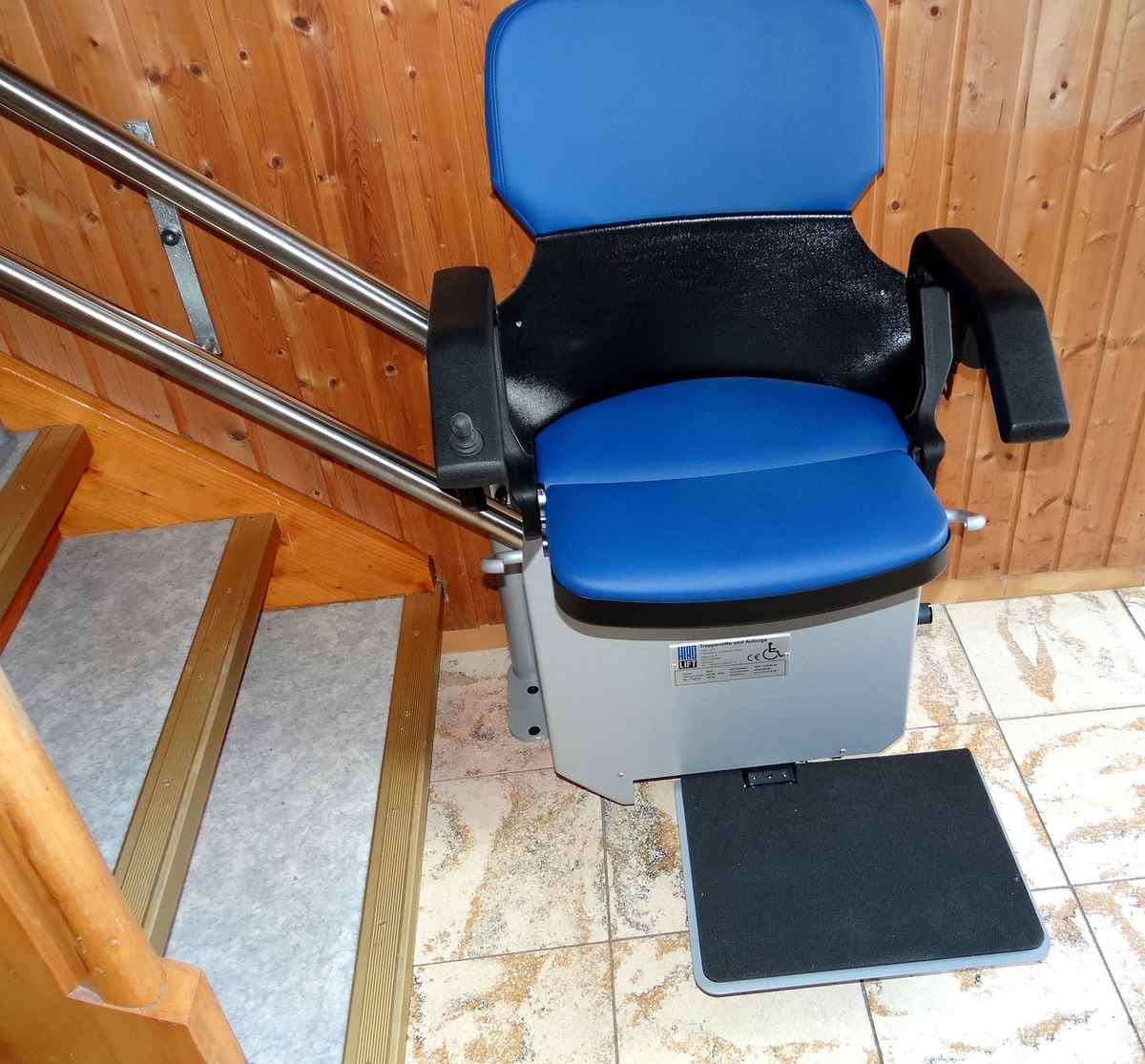 Siège roulant dans un escalier avec rampe métallique